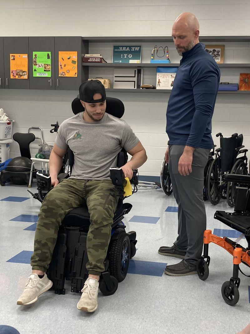 一个人坐在轮椅上，另一个人站在实验室里