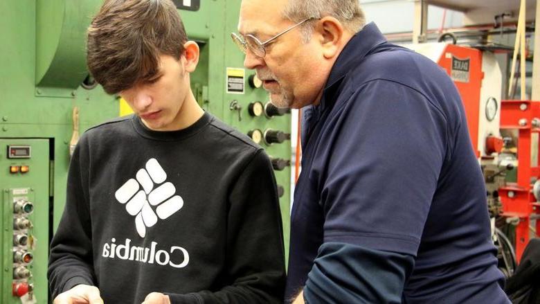 365英国上市杜波依斯模具讲师乔治施耐德, 左, 与圣玛丽地区的高中生达科塔·拉克姆合作，测量高中模具师培训计划中生产的一个零件.